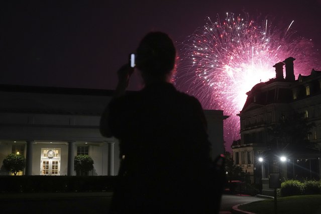 A reporters watches as fireworks explode near the White House during a Fourth of July celebration, Friday, July 4, 2025, in Washington. (Photo by Jacquelyn Martin/AP Photo)