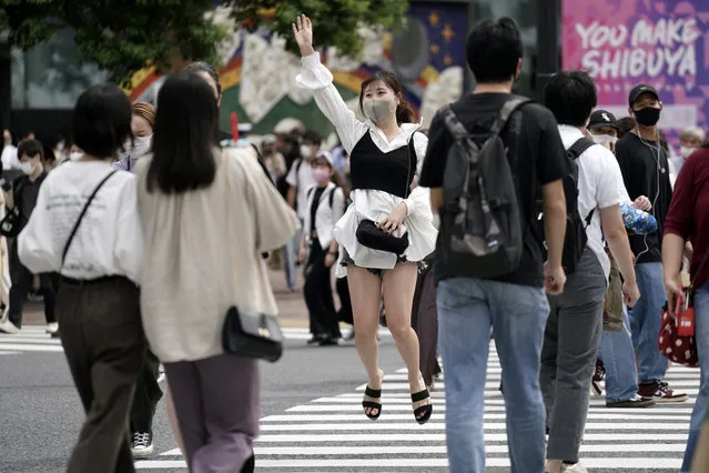 A woman wearing a protective mask to help curb the spread of the coronavirus jumps at Shibuya pedestrian crossings Monday, September 21, 2020, in Tokyo. The Japanese capital confirmed more than 90 coronavirus cases on Monday marking Respect-for-the-Aged Day holiday. (Photo by Eugene Hoshiko/AP Photo)