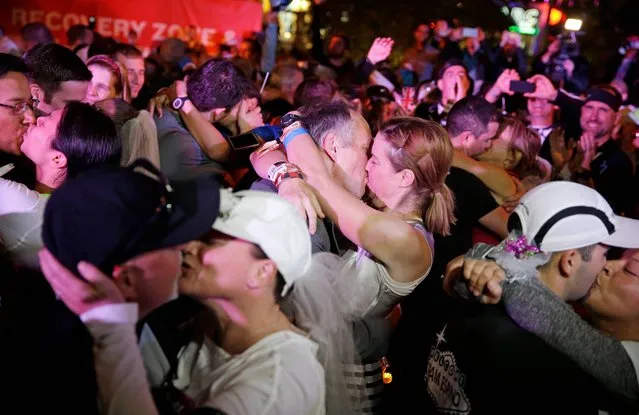 Runners kiss as they get married and renew their vows at the run-thru wedding chapel during the Rock 'n' Roll Las Vegas Marathon along the Las Vegas Strip, Sunday, November 16, 2014, in Las Vegas. (Photo by John Locher/AP Photo)