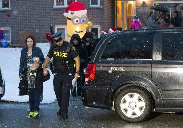 Evan Leversage, who is terminally ill with brain cancer, is taken by a police officer as he is going to get a tour of the neighbourhood to see all the Christmas lights with his mother Nicole Wellwood (L) in St. George, Ontario, Canada October 24, 2015. (Photo by Mark Blinch/Reuters)