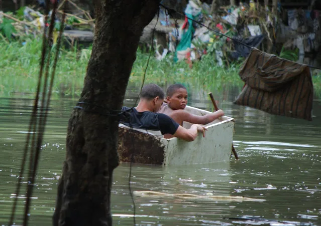 Two boys float in an old wooden box in an area flooded by heavy rains caused by Hurricane Matthew, in La Puya slum, in the Arroyo Hondo creek in Santo Domingo, Dominican Republic, Tuesday, October 4, 2016. Matthew roared into the southwestern coast of the island of Hispaniola with devastating storm conditions as it headed north toward Cuba and the eastern coast of Florida. (Photo by Ezequiel Abiu Lopez/AP Photo)