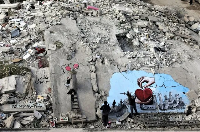 Syrian artists Aziz Asmar and Salam Hamed paint street art on the rubble of damaged buildings in the aftermath of a deadly earthquake, in the rebel-held town of Jandaris, Syria on February 22, 2023. (Photo by Khalil Ashawi/Reuters)