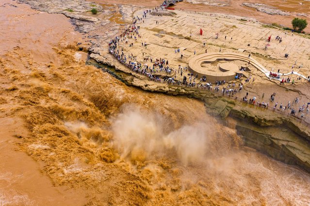 An aerial view of people visiting the roaring Hukou Waterfall on the Yellow River on August 11, 2025 in Yan'an, Shaanxi Province of China. Hukou waterfall is witnessing an increasing water flow lately. (Photo by Liu Yijiang/VCG via Getty Images)