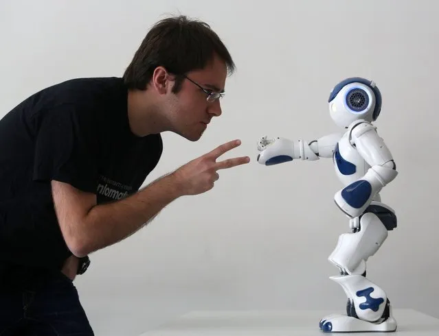 Student Alejadro Bordallo plays rock-scissors-paper with a robot programmed by scientists to use artificial intelligence to learn strategy as they play, part of the Edinburgh International Science festival at the National Museum of Scotland, on April 2, 2013. (Photo by David Cheskin/PA Wire)