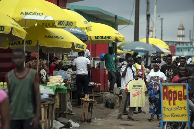 Street vendors use parasols reading “Abobo ADOland” in reference to the Ivory Coast President Alassane Ouattara, who is known as ADO, at Abobo neighborhood in Abidjan, Ivory Coast, Monday, November 2, 2020. (Photo by Leo Correa/AP Photo)