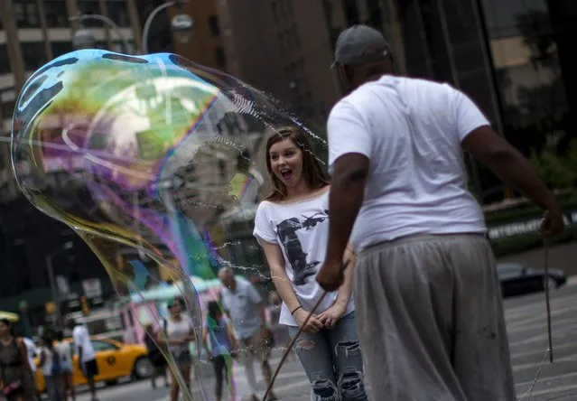 A man circles a tourist in a giant soap bubble at Columbus Circle near Central Park in New York on a warm summer day July 21, 2015. (Photo by Mike Segar/Reuters)