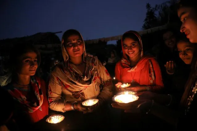Pakistani Hindu refugees hold candles as they celebrate on the eve of Diwali, the Hindu festival of lights, during a visit by a Bharatiya Janata Party (BJP) politician, in New Delhi, India on November 13, 2020. (Photo by Anushree Fadnavis/Reuters)