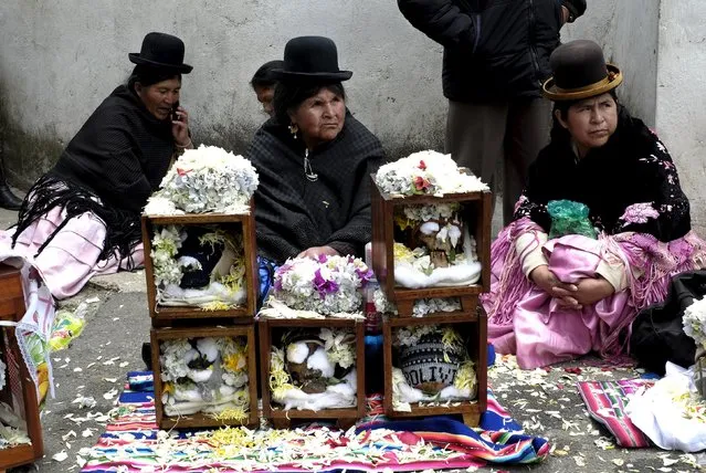 Aymara women sit near skulls placed on the floor during a ceremony held for the "Dia de las natitas" (Day of the Skull) celebrations at the General Cemetery of La Paz, November 8, 2015. (Photo by David Mercado/Reuters)