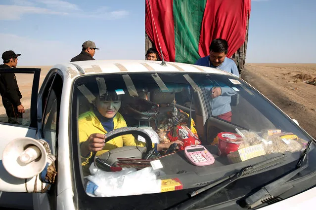 A woman stops to sell food to truck drivers near the border with China at Khanbogd Soum in the Gobi desert, Mongolia, October 31, 2017. A megaphone mounted on her car plays a recording letting drivers know she can offer food, water and fresh meat. (Photo by Bazarsukh Rentsendorj/Reuters)