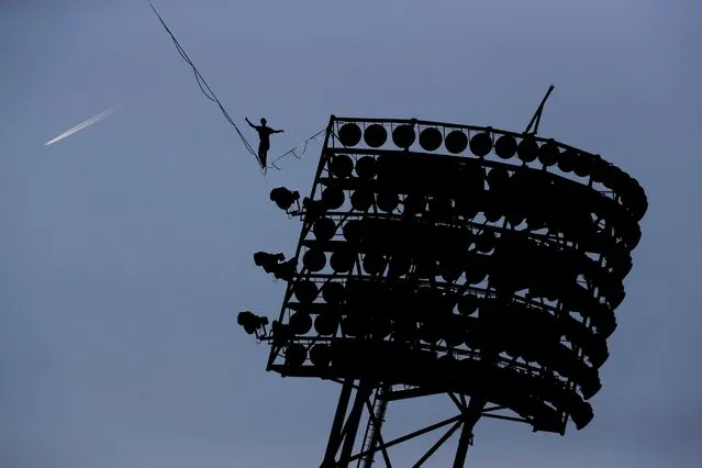 A man balances as he walks on the rope between stadium floodlight poles in the Olympic park Munich, Germany, October 16, 2016. (Photo by Matthias Schrader/AP Photo)