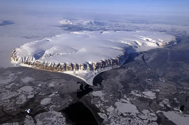 This April 20, 2013 NASA handout image shows Saunders Island and Wolstenholme Fjord with Kap Atholl in the background seen during an IceBridge survey flight near Qaasuitsup, Greenland. Sea ice coverage in the Fjord ranges from thicker, white ice seen in the background, to thinner grease ice and leads showing open ocean water in the foreground. (Photo by NASA HO via Michael Studinger/AFP Photo)