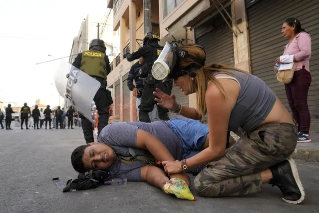 A woman tends to an anti-government protester who fell during a march against President Dina Boluarte in Lima, Peru, Thursday, January 19, 2023. Protesters are seeking immediate elections, the resignation of Boluarte, the release from prison of ousted President Pedro Castillo and justice for protesters killed in clashes with police. (Photo by Martin Mejia/AP Photo)