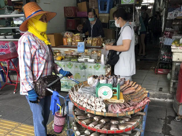 A vendor wearing a face covering to help prevent the spread of coronavirus sells fish from a pushcart outside a produce market in central Bangkok on Wednesday, December 23, 2020. Thailand has kept the coronavirus largely in check for most of the year but is facing a challenge from a large outbreak of the virus among migrant workers linked to a major seafood market close to the Thai capital. (Photo by Adam Schreck/AP Photo)