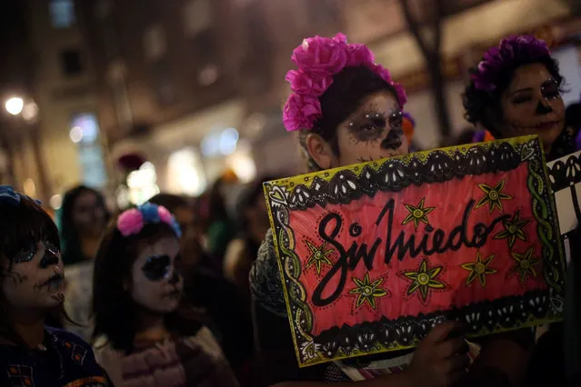 An activist with her face painted to look like popular Mexican figure “Catrina” holds a sign in a march against femicides during the Day of the Dead in Mexico City, Mexico, November 1, 2016. The sign reads; “Without fear”. (Photo by Edgard Garrido/Reuters)