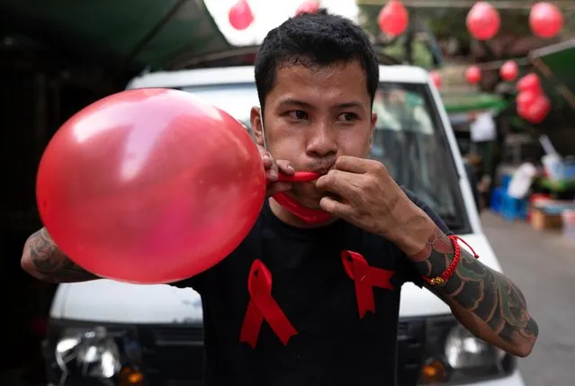 A man wearing red ribbons inflates a balloon as he takes part in a campaign against the military coup in Yangon, Myanmar on February 5, 2021. (Photo by Reuters/Stringer)