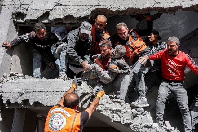 Palestinian civil defence members hand over to each other a child that was rescued following Israeli bombardment on the four-storey Muqat family house in the Zarqa neighbourhood in the north of Gaza City on October 26, 2024 amid the ongoing war in the Palestinian territory between Israel and Hamas. (Photo by Omar Al-Qattaa/AFP Photo) 