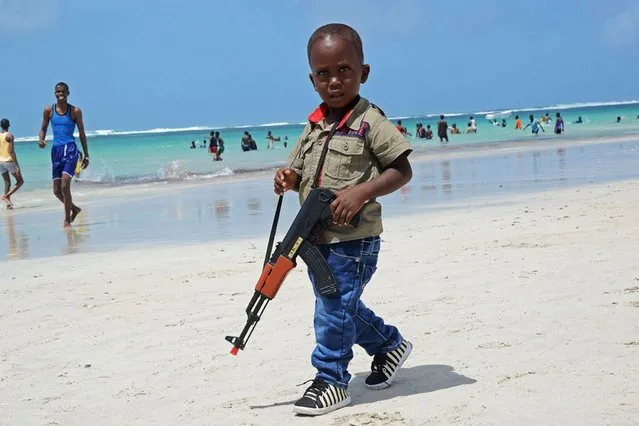 A Somali boy walks with a toy gun along the Lido Beach near Mogadishu, on August 9, 2013. (Photo by Mohamed Abdiwahab/AFP Photo)