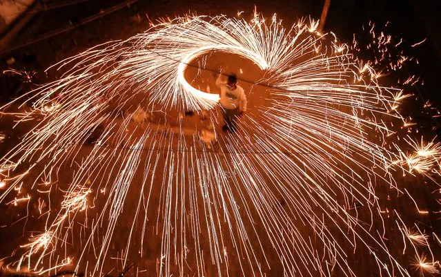 A Palestinian youth swings a homemade fireworks sparkler, as people celebrate on the night ahead of the Muslim holy fasting month of Ramadan, in Gaza City on April 11, 2021. (Photo by Mahmud Hams/AFP Photo)